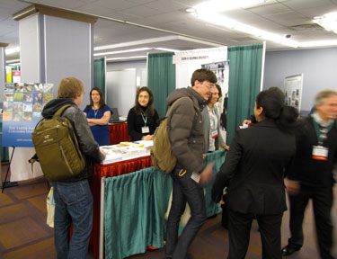 Photo of CIESIN booth at AAG 2012 conference shows booth workers and attendees.